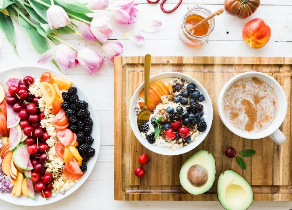 Mesa con fruta fresca, avena y flores vista desde arriba