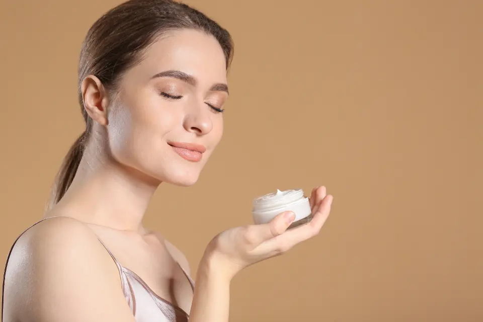 Mujer con los ojos cerrados sosteniendo un tarro de crema